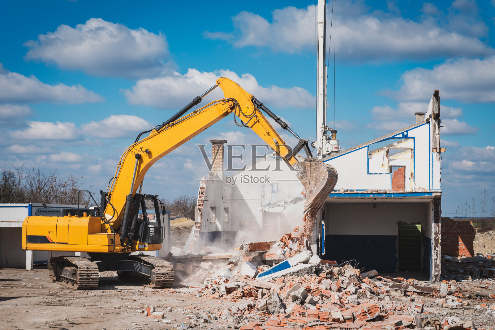 大型建筑机械正在拆除建筑工地上的房屋照片摄影